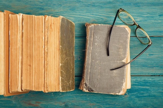 Photo stack of antique books and glasses on blue wooden background