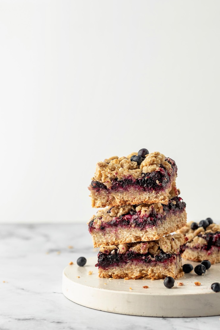 Photo stack of baked oatmeal squares with fresh blueberry on white tray with text space vertical recipe