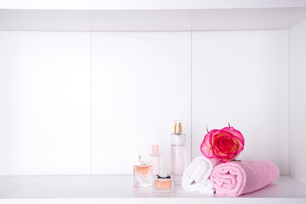 Stack of bath towels with rose on light background