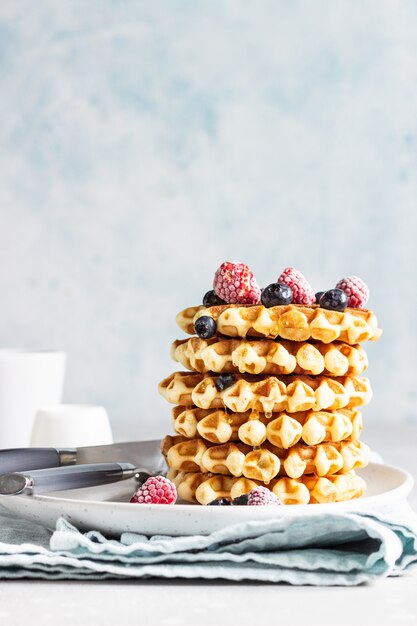 Stack of belgian vanilla waffles with berry (blueberry and raspberry) and honey.