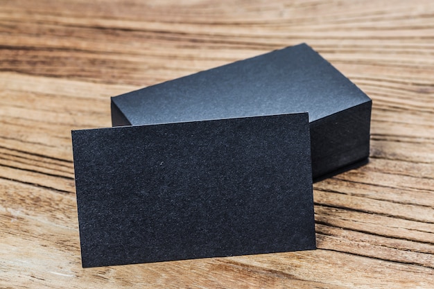 Stack of blank black business cards on wooden background