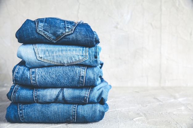 Stack of blue jeans on a gray background