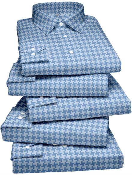 A stack of blue linen shirts with a white shirt on top.