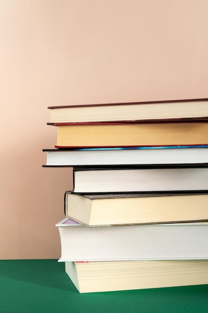 Stack of books against pink background copy space