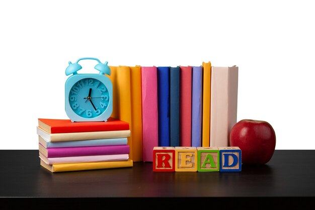 Stack of books and apple on tabletop against white background