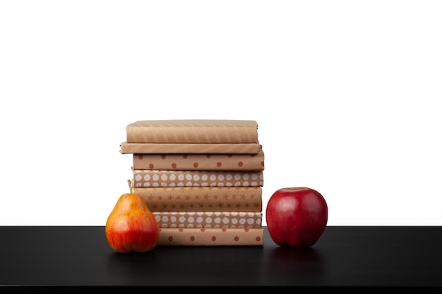 Stack of books and apple on tabletop against white background