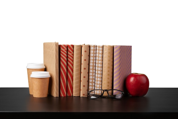 Stack of books and apple on tabletop against white background