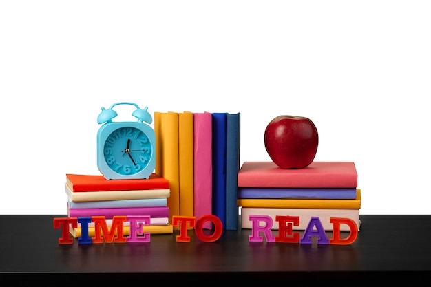 Photo stack of books and apple on tabletop against white background