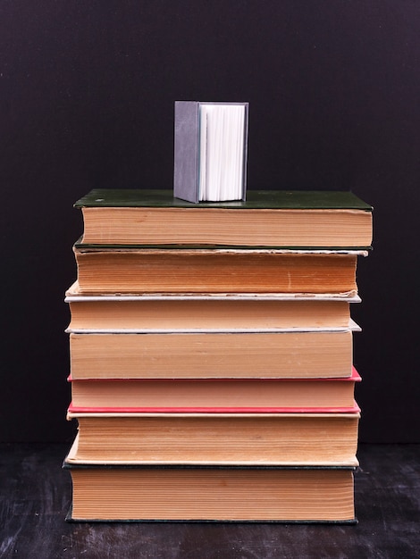 Stack of books on a black background with small book on top