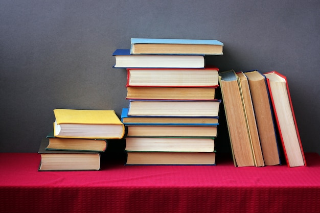 A stack of books in the colored covers on the table with a red tablecloth. Still life with books.