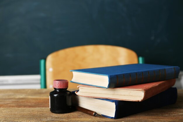 Stack of books on desk on blackboard background