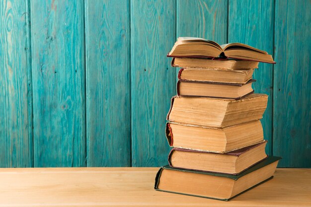 Stack of books on the desk over wooden background