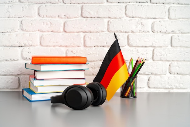 Stack of books and flag of germany on desk german language learning concept