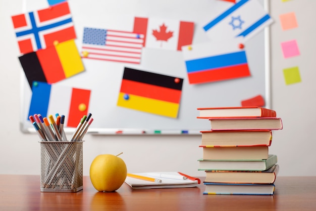 Foto pila di libri davanti alla lavagna della scuola con le bandiere di diversi paesi