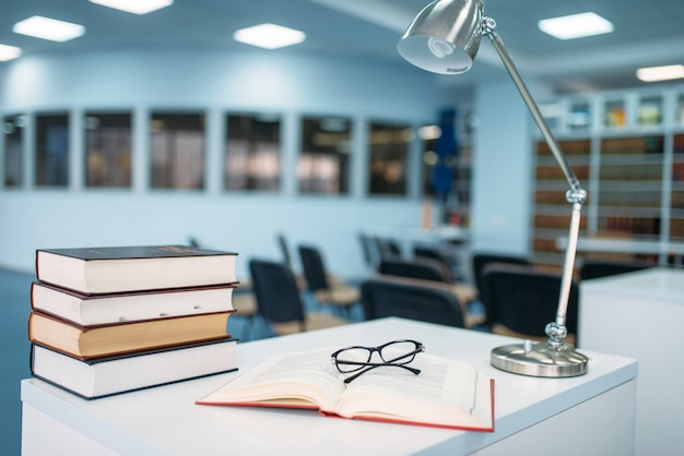 Stack of books and glasses on table in library