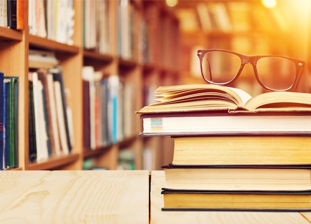 Stack of books in the library and blur bookshelf background            - Image