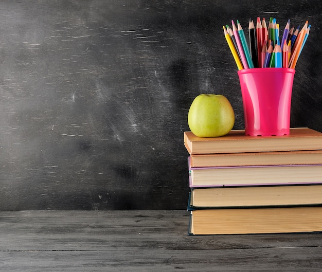 Stack of books and  multi-colored wooden pencils