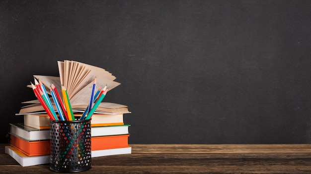 Stack of books and stationery on the background of the school board. Education and back to school concept.