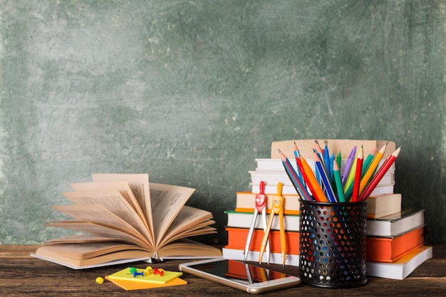 Stack of books and stationery on the background of the school board. Education and back to school concept.