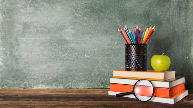 A Stack of books and stationery on the background of the school board