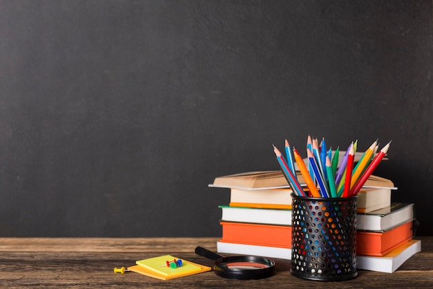 Stack of books and stationery on the background of the school board