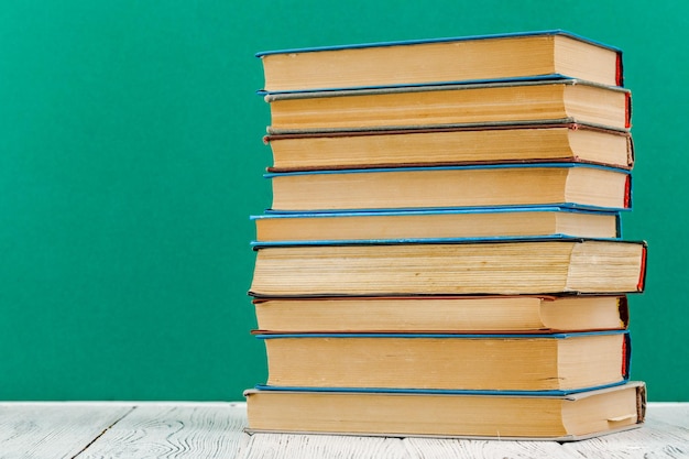 A stack of books on a white table on a green background.