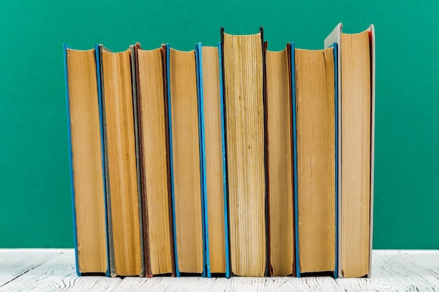 A stack of books on a white table on a green background.