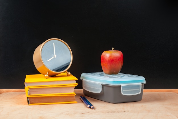 Stack of books with apple and pencil on table