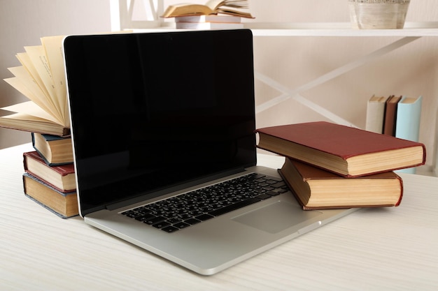 Stack of books with laptop on table close up