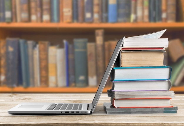 Photo stack of books with laptop on table