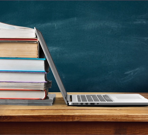 Stack of books with laptop on table