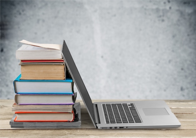 Stack of books with laptop on table