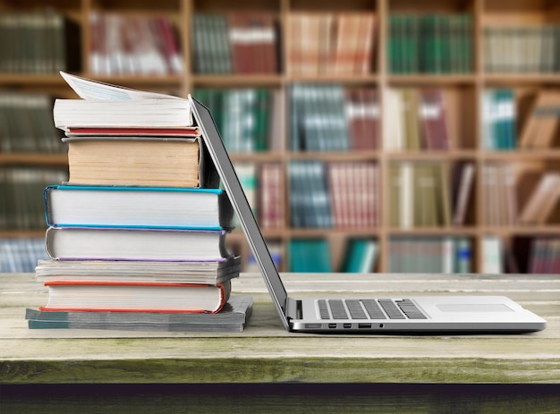 Stack of books with laptop on table