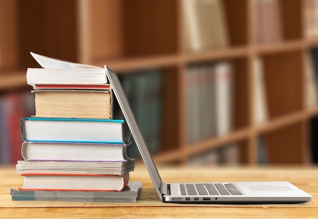 Stack of books with laptop on table