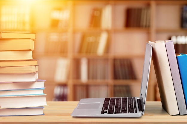 Stack of books with laptop on table