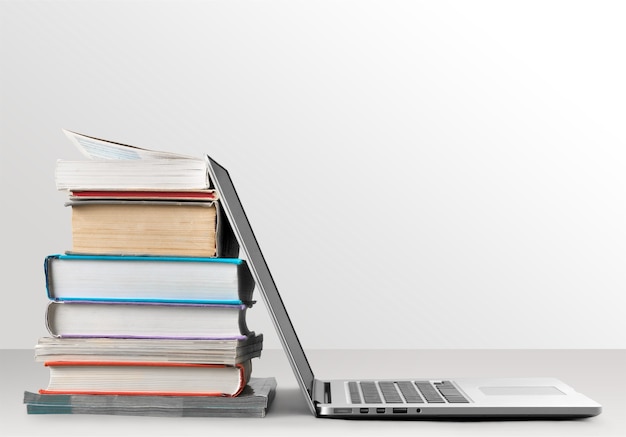 Stack of books with laptop on table