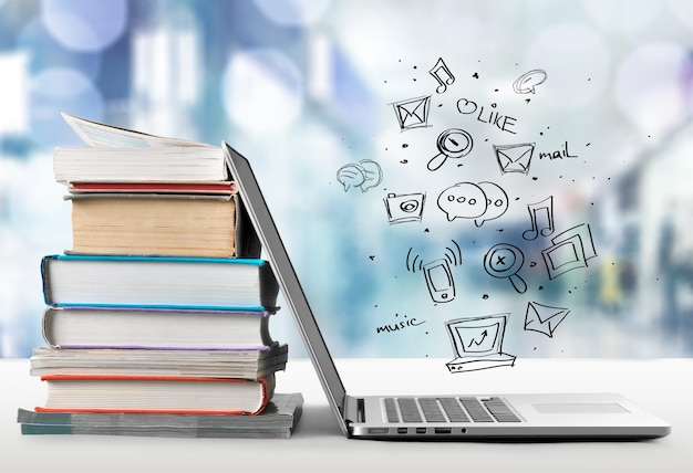 Stack of books with laptop on table