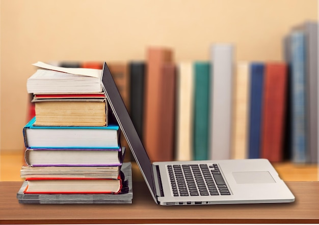 Stack of books with laptop on wooden table