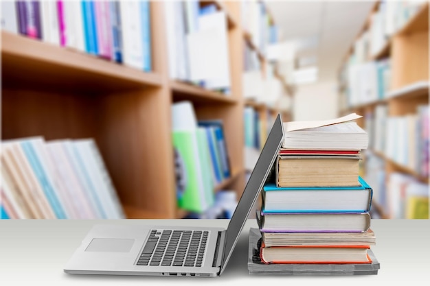 Stack of books with laptop on wooden table