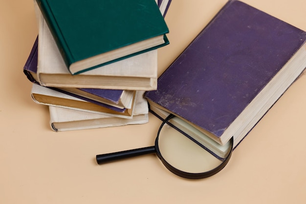 A stack of books with a magnifying glass highlighted on a beige background Search for information