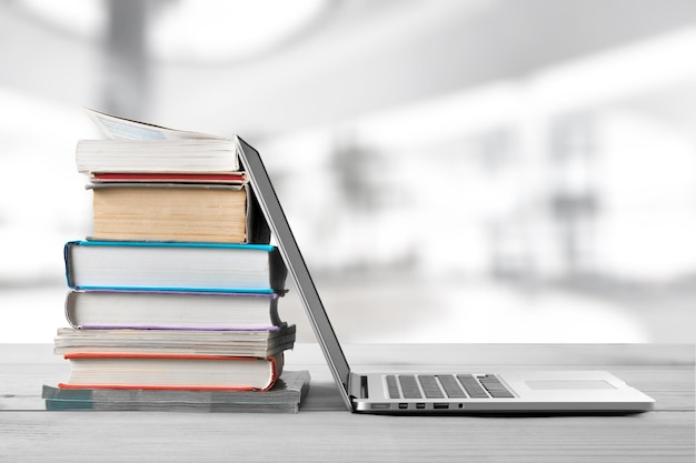 Stack of books with a modern laptop on the table