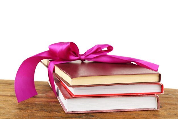 Stack of books with ribbon on table isolated on white