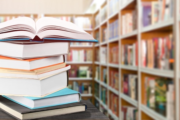 A stack of books on a wood table. Library in the background.