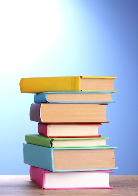 Stack of books on wooden table on blue background