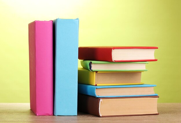 Stack of books on wooden table on green background