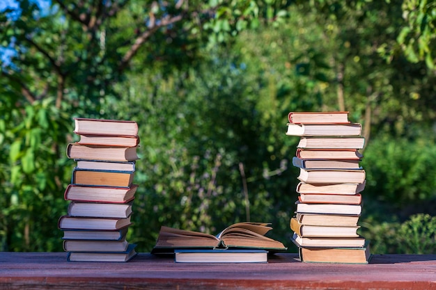 Stack of books on wooden table over nature background outdoors