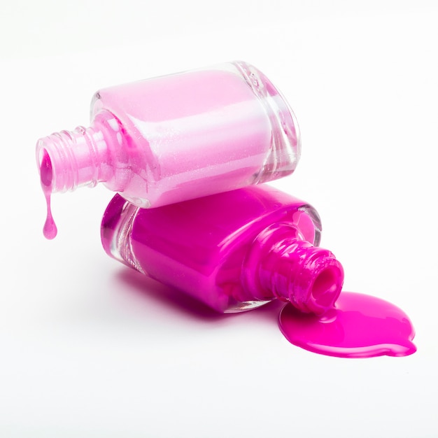 Stack of bottles with spilled nail polish over white background