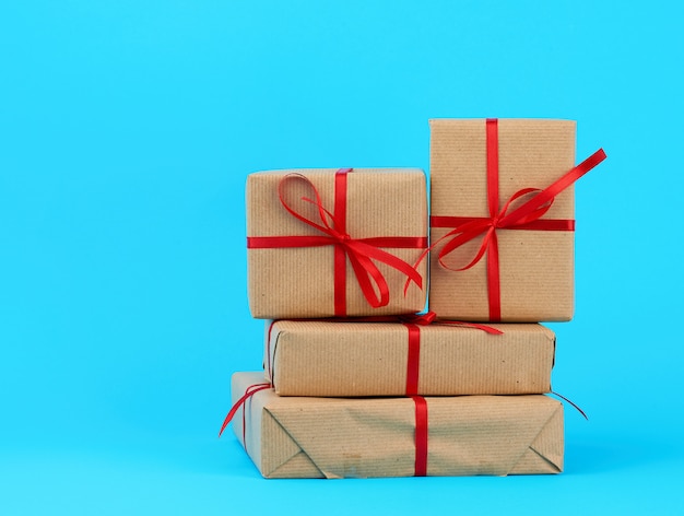 Stack of boxes wrapped in brown paper and tied with a red bow, gifts on blue