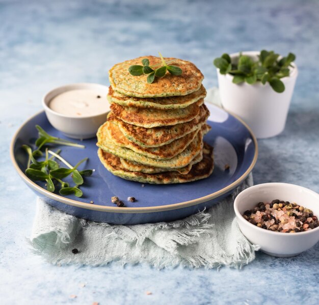 Stack of broccoli or spinach pancakes with yoghurt or cream sour dressing and microgreen