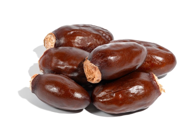 Stack of brown lychee pits on white isolated background